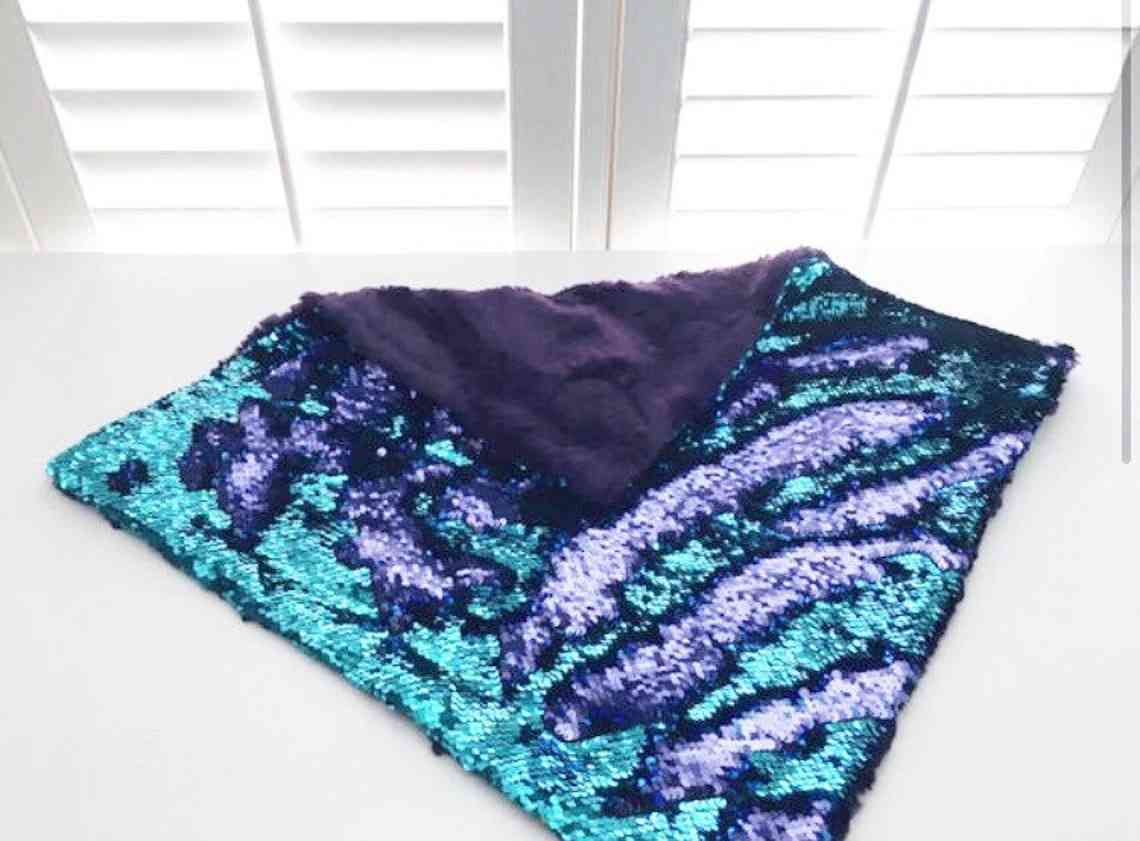 Weighted lap pad with reversible sequins in turquoise and purple.