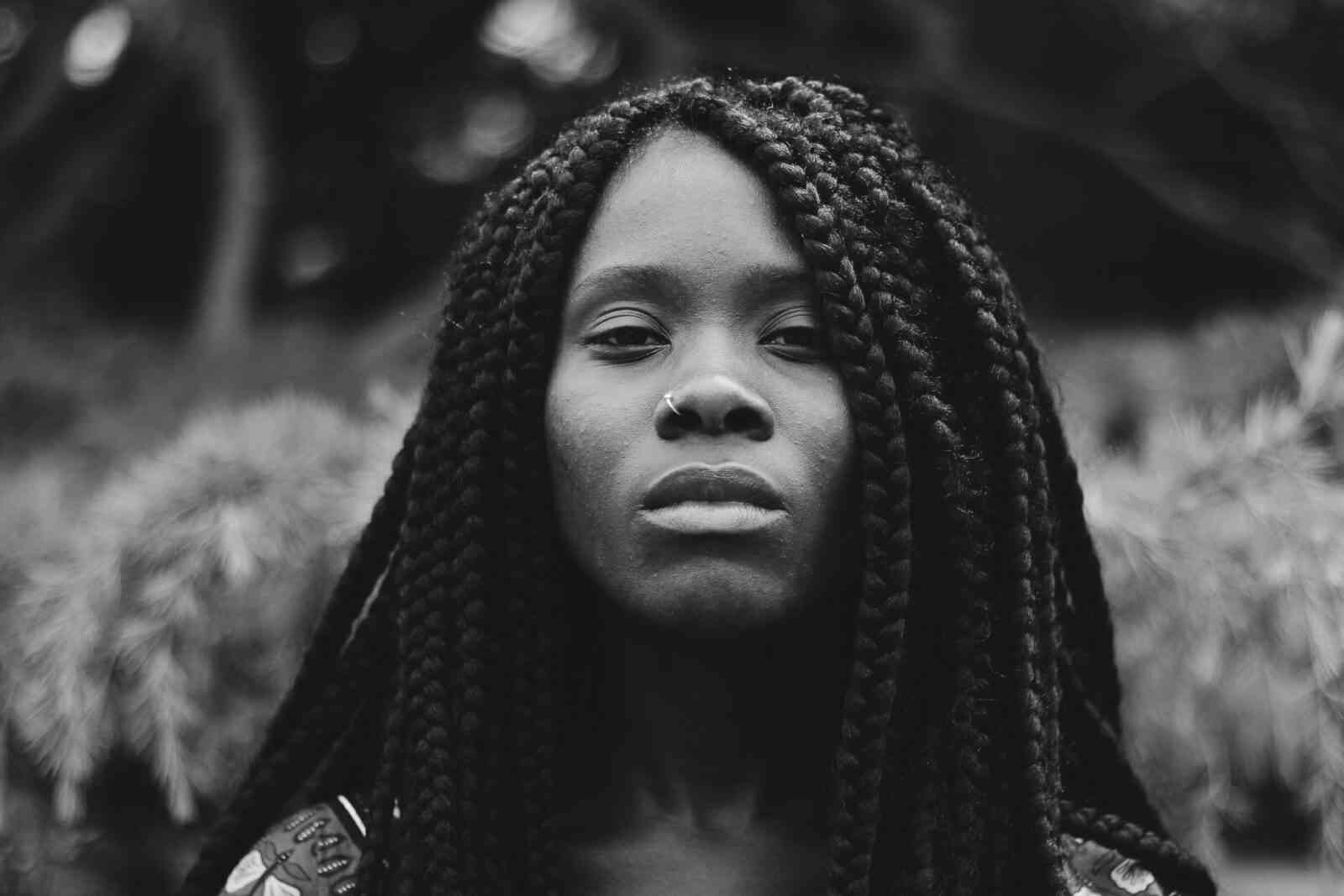 Anhedonia: a common depression symptom. It involves numbness and inability to feel pleasure. Image shows a sad, thoughtful Black woman with braids.