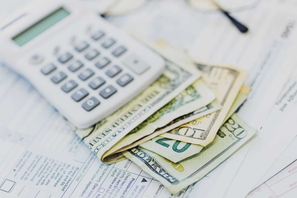 Tips for managing money with a disability. Calculator and cash sitting on a table with tax forms.