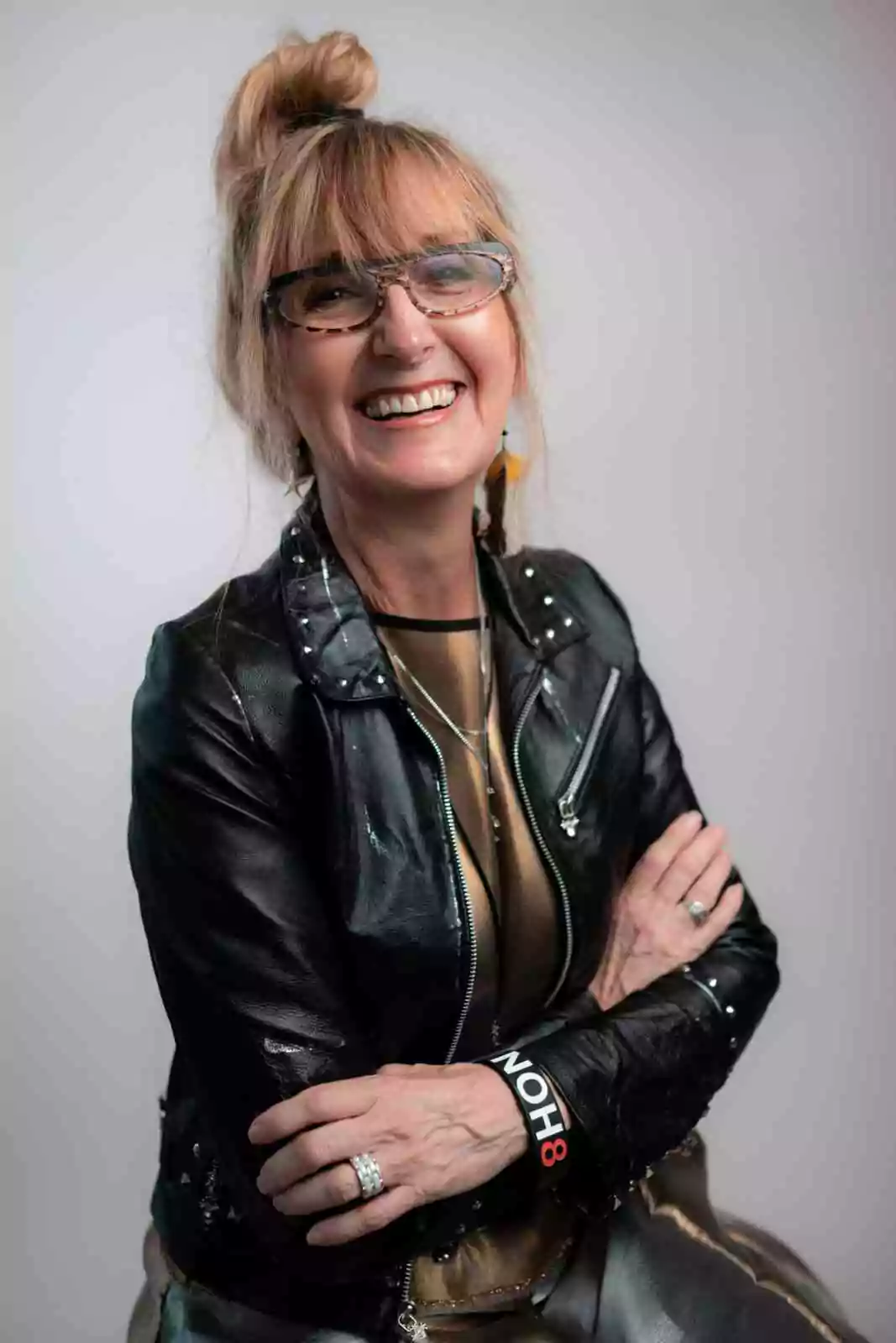 Nancy Volpe Beringer, a white woman with blonde hair and glasses. She is wearing a brown shirt and black leather jacket.
