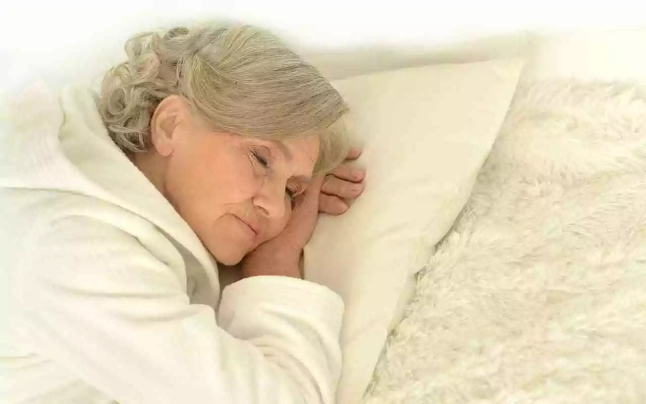 Senior woman sleeping in bed. Bedding to stop painsomnia -- insomnia caused by chronic pain.