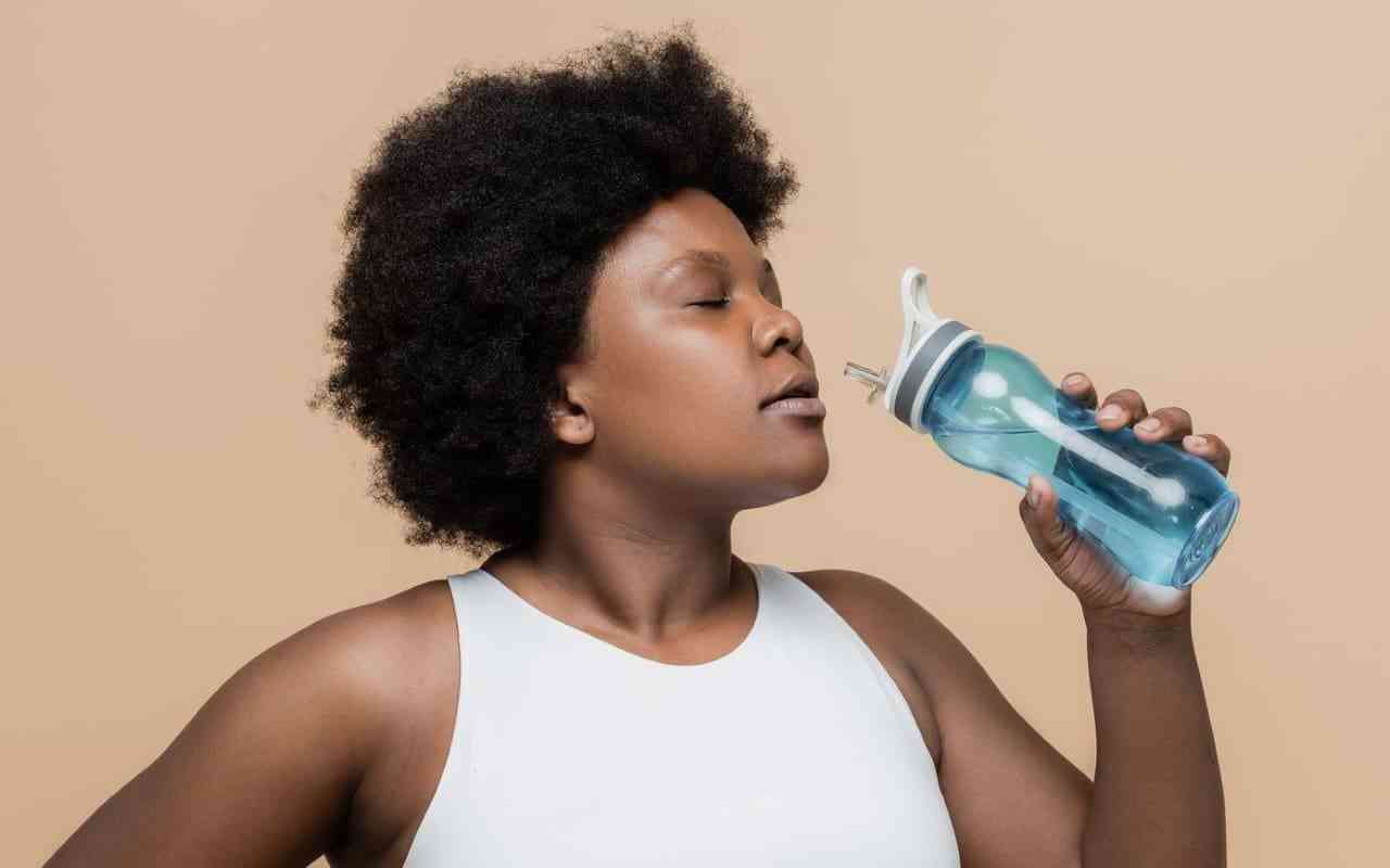 Exercise guide for people with depression. Woman drinking from water bottle.