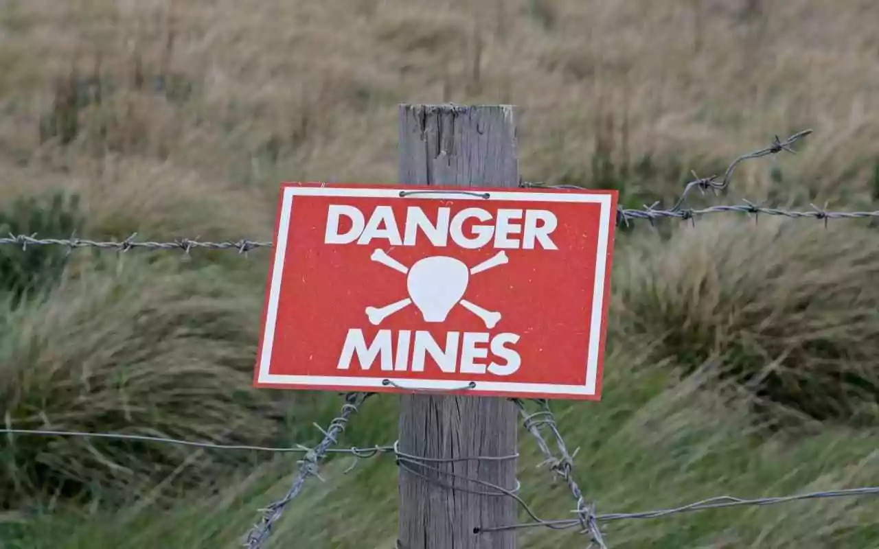 How to navigate the minefield of getting physical health care when you live with mental illness. Minefield warning sign attached to barbed wire.
