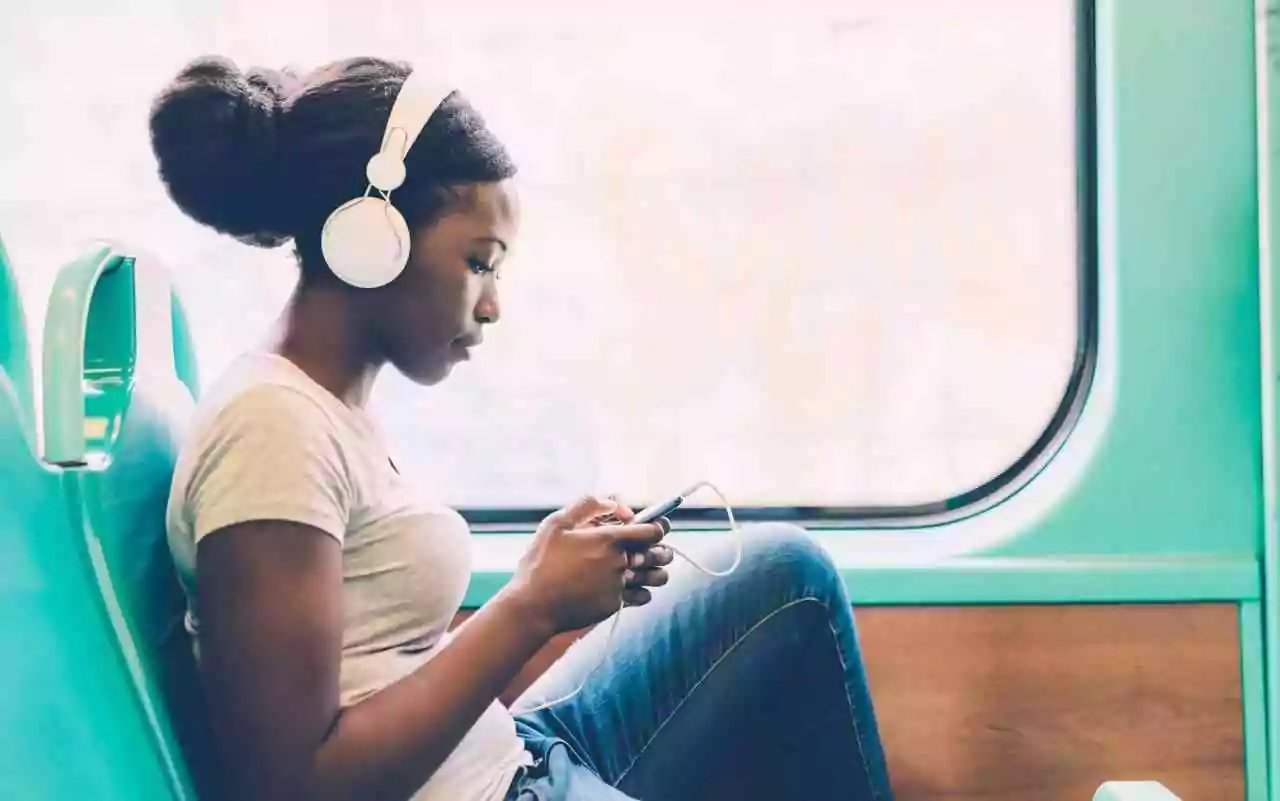 Misophonia coping tips. Woman listening to music with headphones on train.