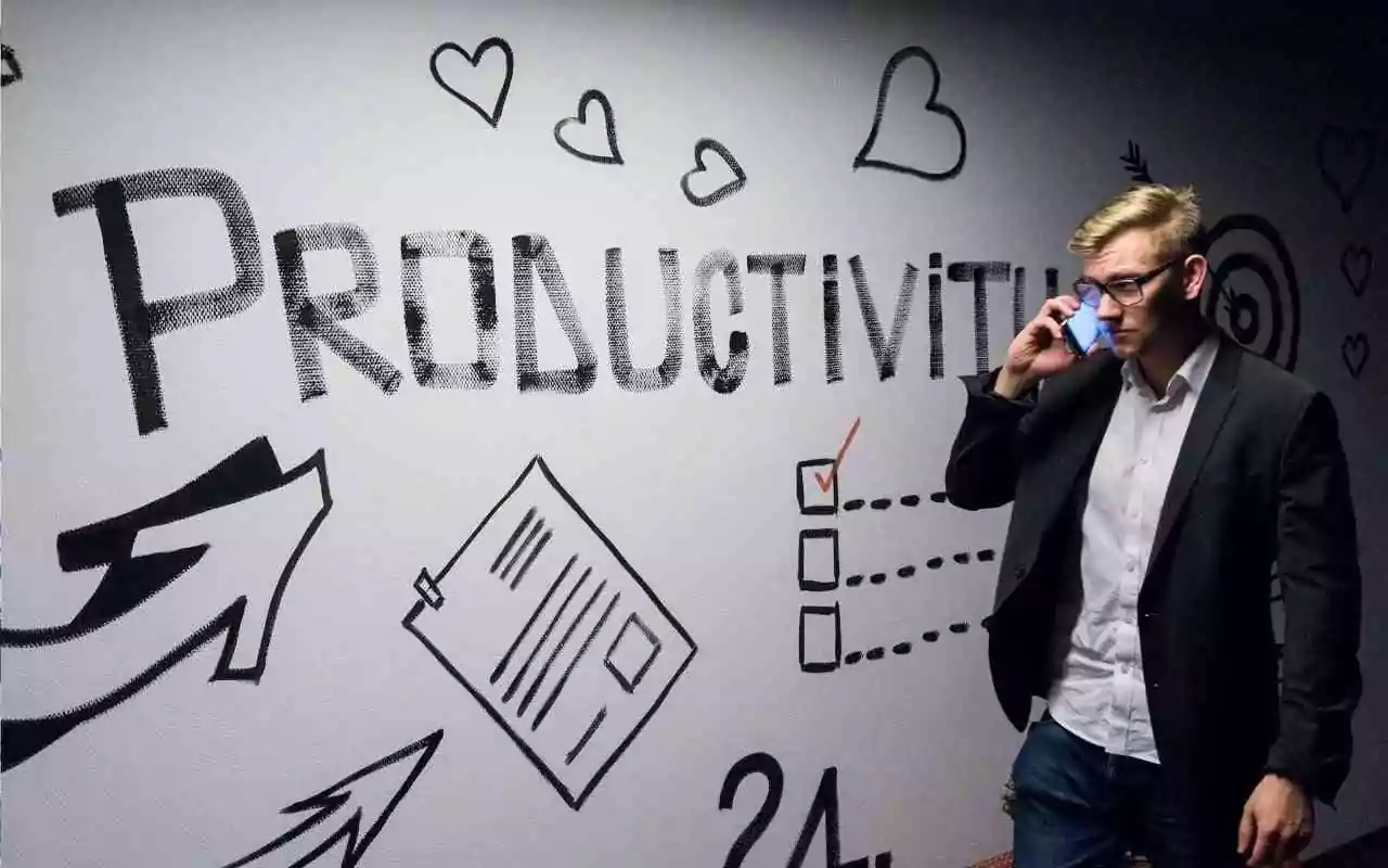 Man on cell phone standing in front of a white board with the word Productivity written on it.