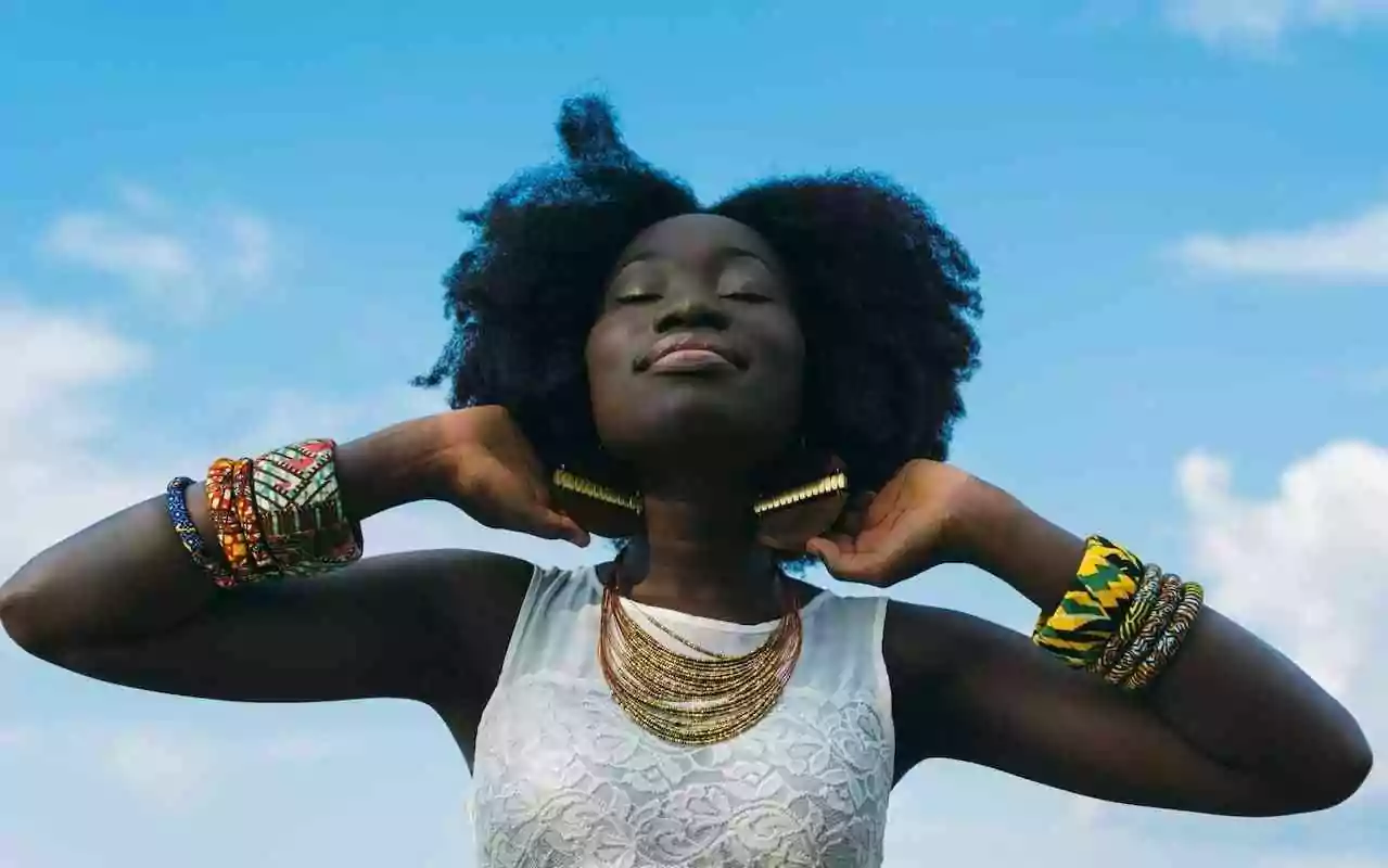 How to practice self-compassion as a person of color who experiences racism. Young Black woman with natural hair looking up at the sky.