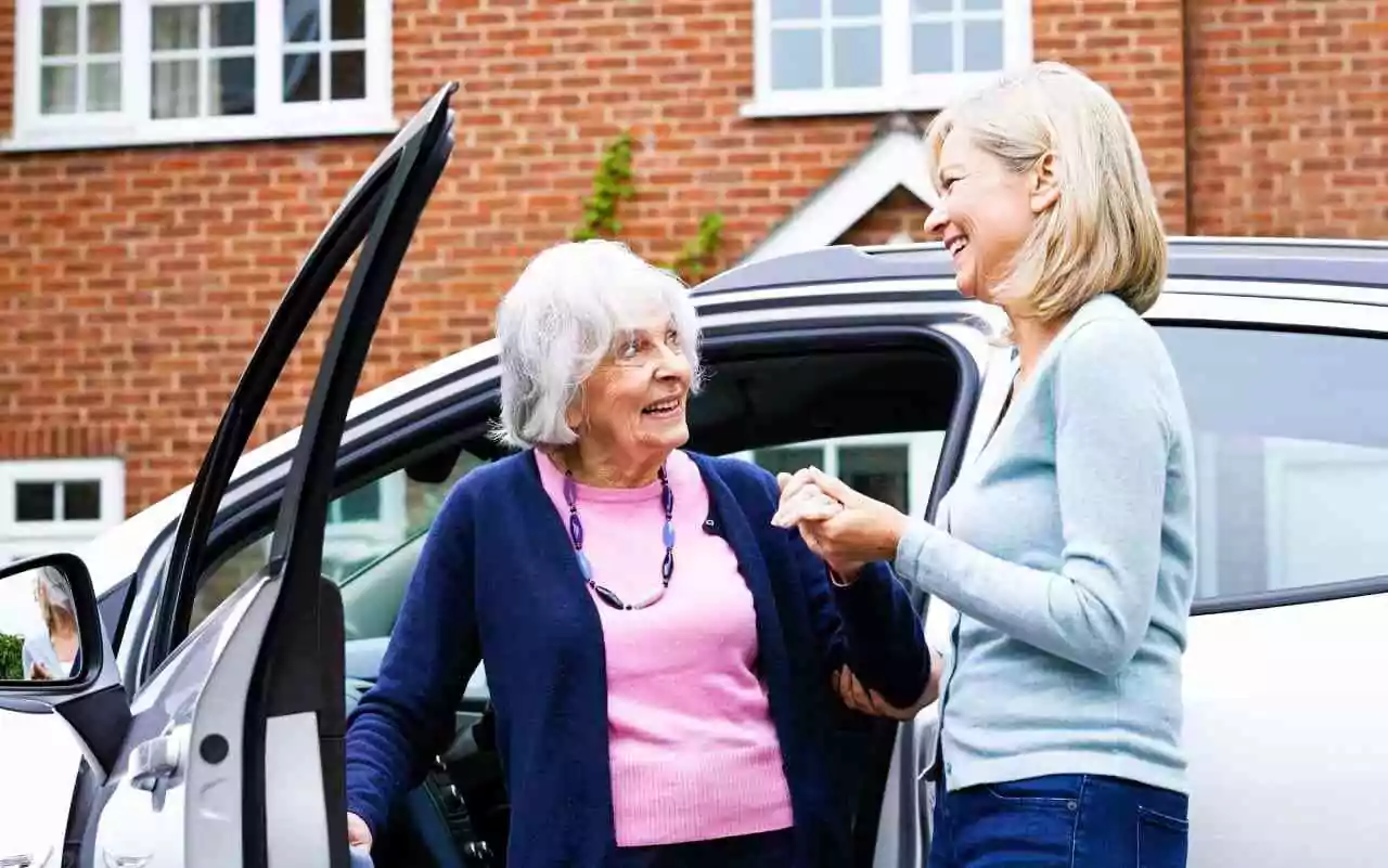 Caregiver helping senior citizen get out of car.
