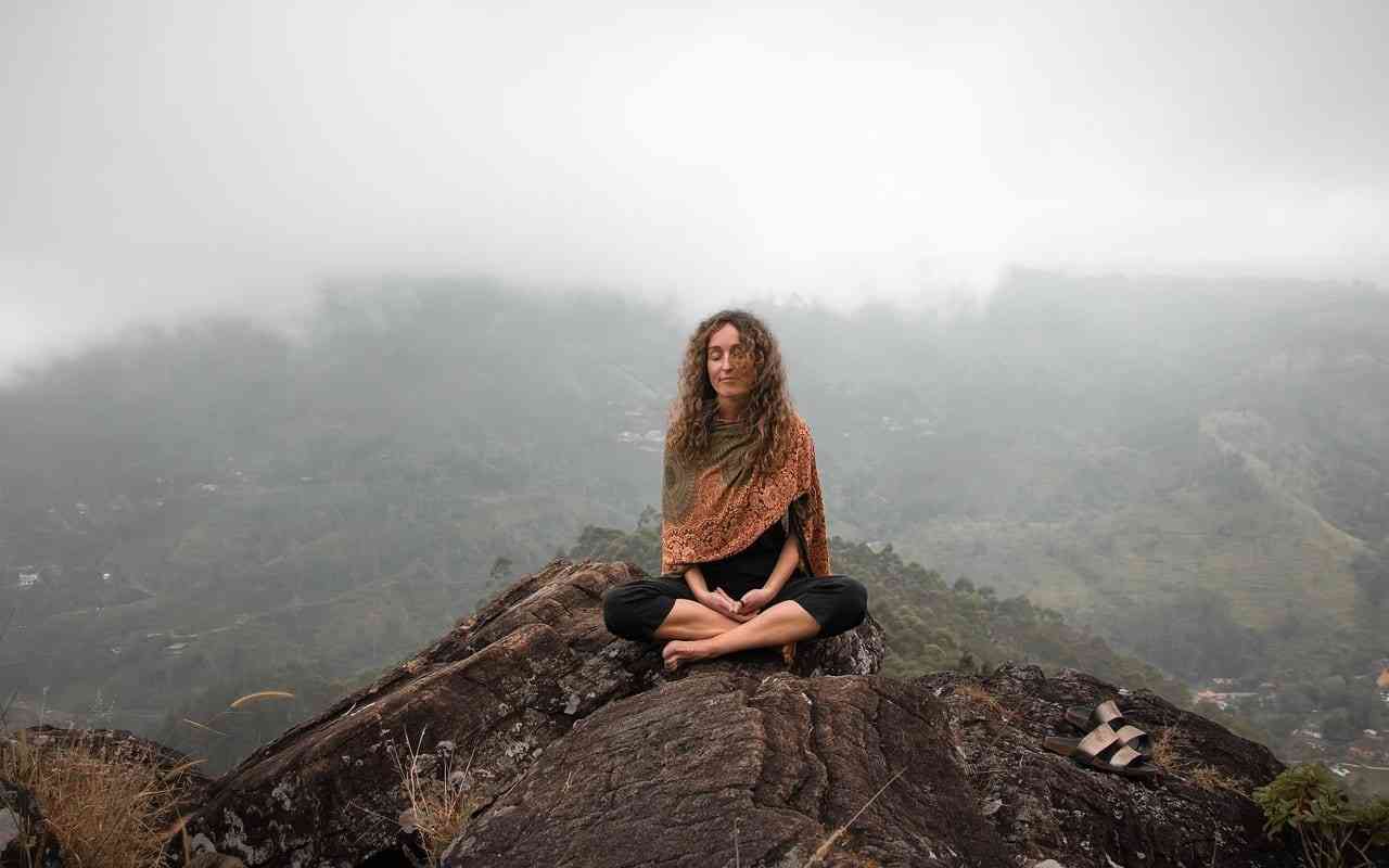 Woman meditating on a mountain.