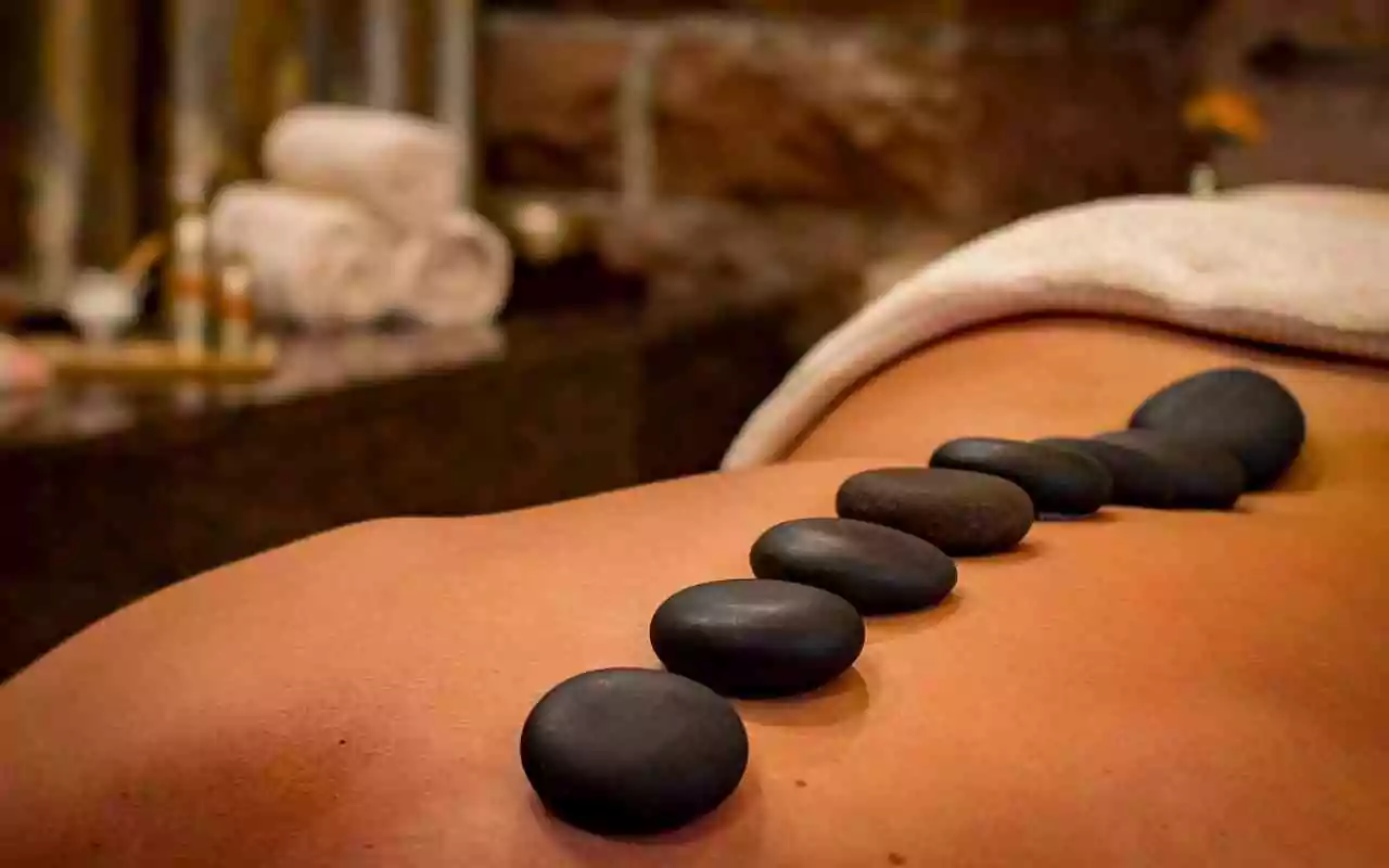 Types of massages. Person receiving hot stone massage.