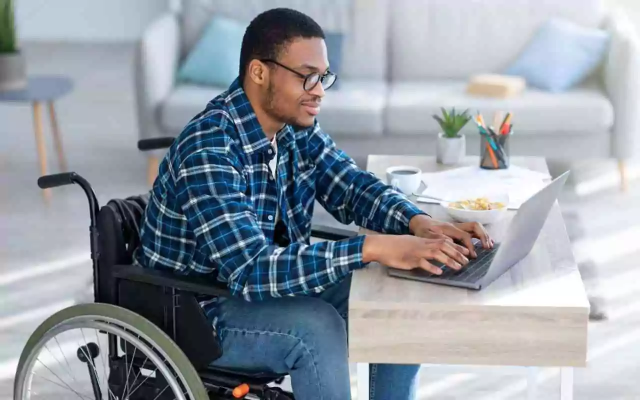 Tips for applying to Ph.D. programs with a disability. Man in wheelchair using laptop.
