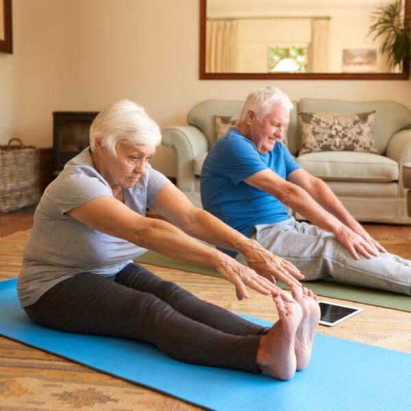 Parkinson's disease exercise guide. Older couple stretching on yoga mats.