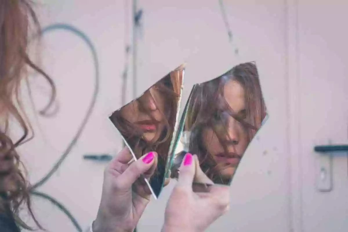 Body image distortion. Teen girl looking at her reflection in a broken mirror.