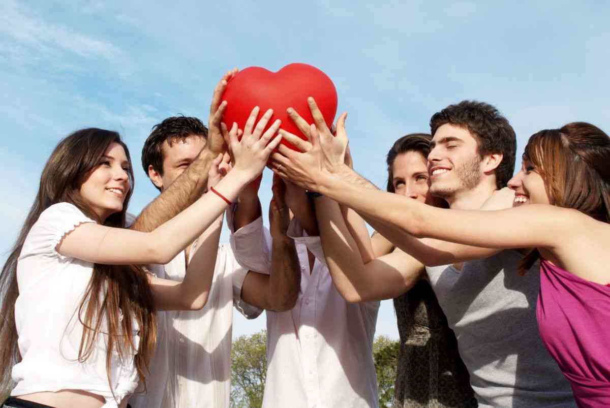 Building meaningful friendships in adulthood. Group of friends holding up a plush heart toy.