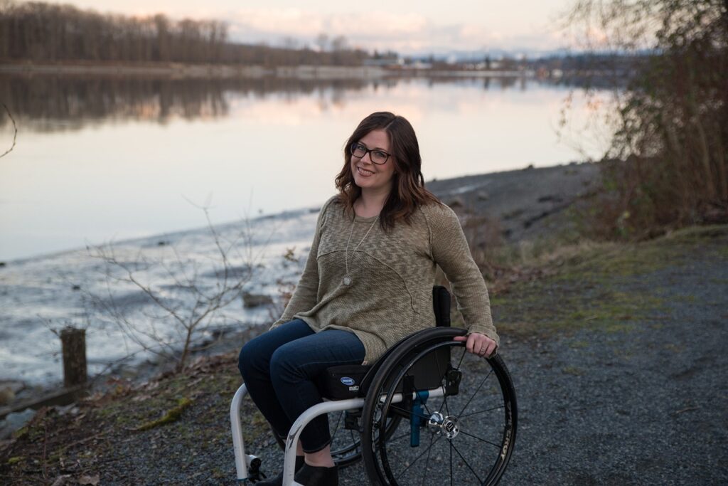 Woman in wheelchair on a path by the water.