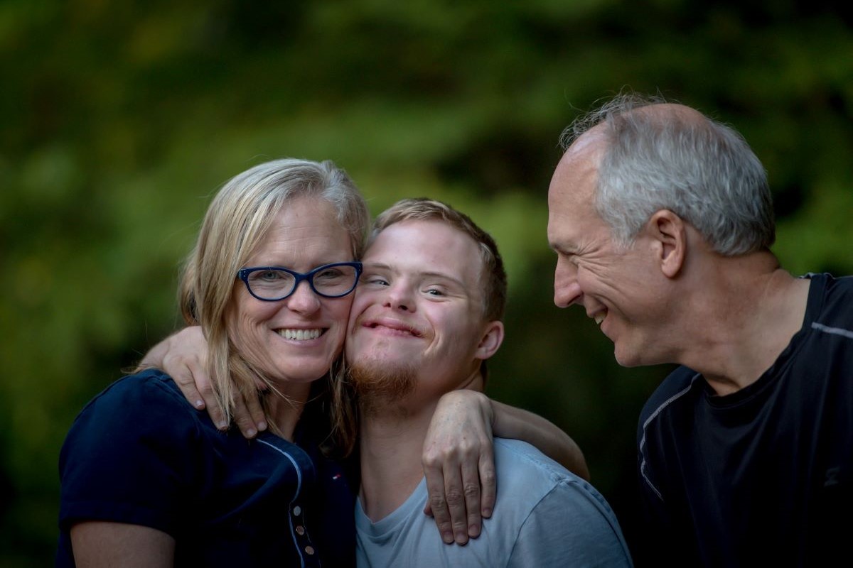 Parents hugging their adult son with an intellectual disability.
