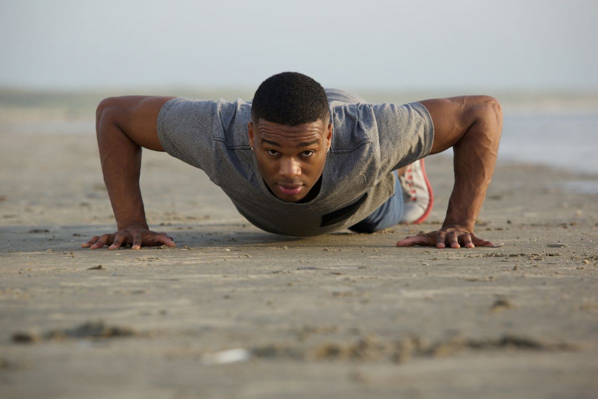 Strength exercises for men. Man doing push-ups on the beach.