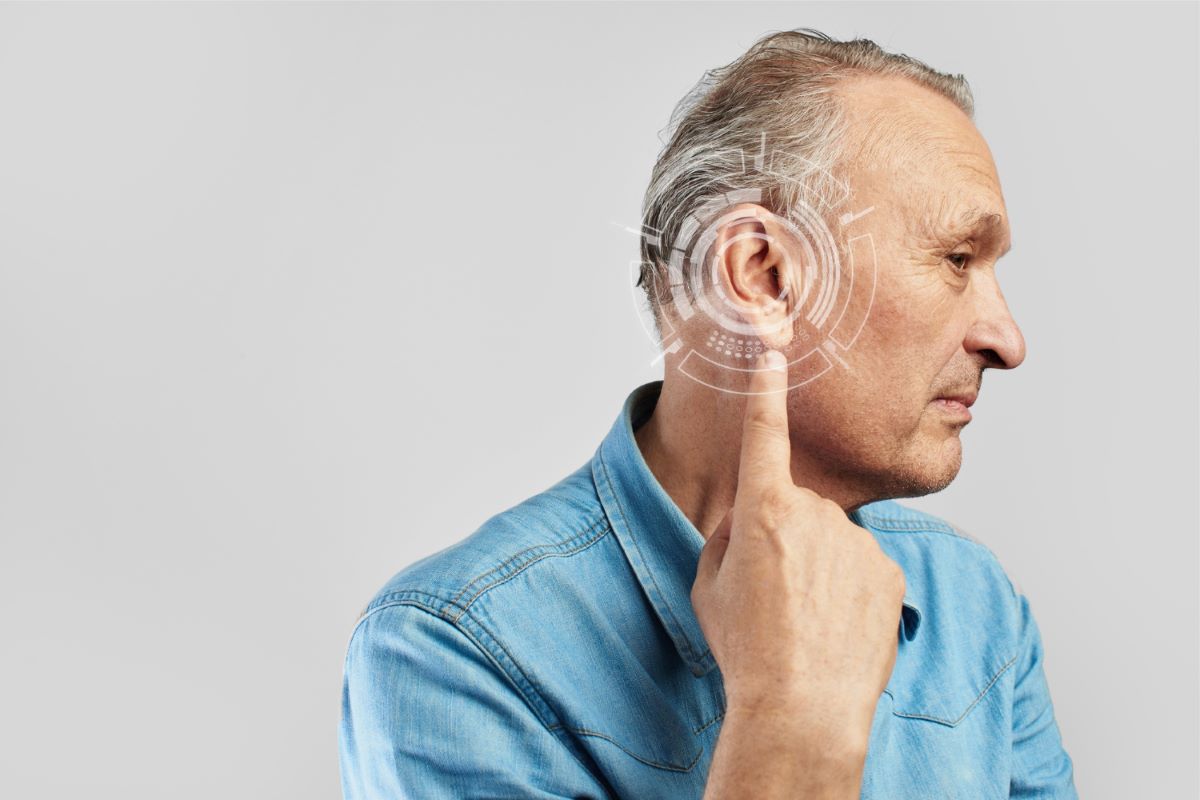 Older man pointing to his ear.
