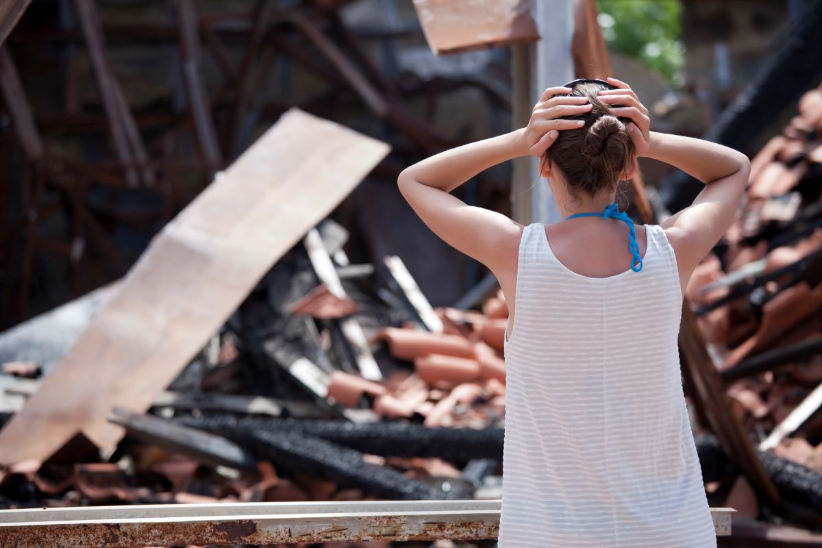 Woman looking at the aftermath of a house fire.