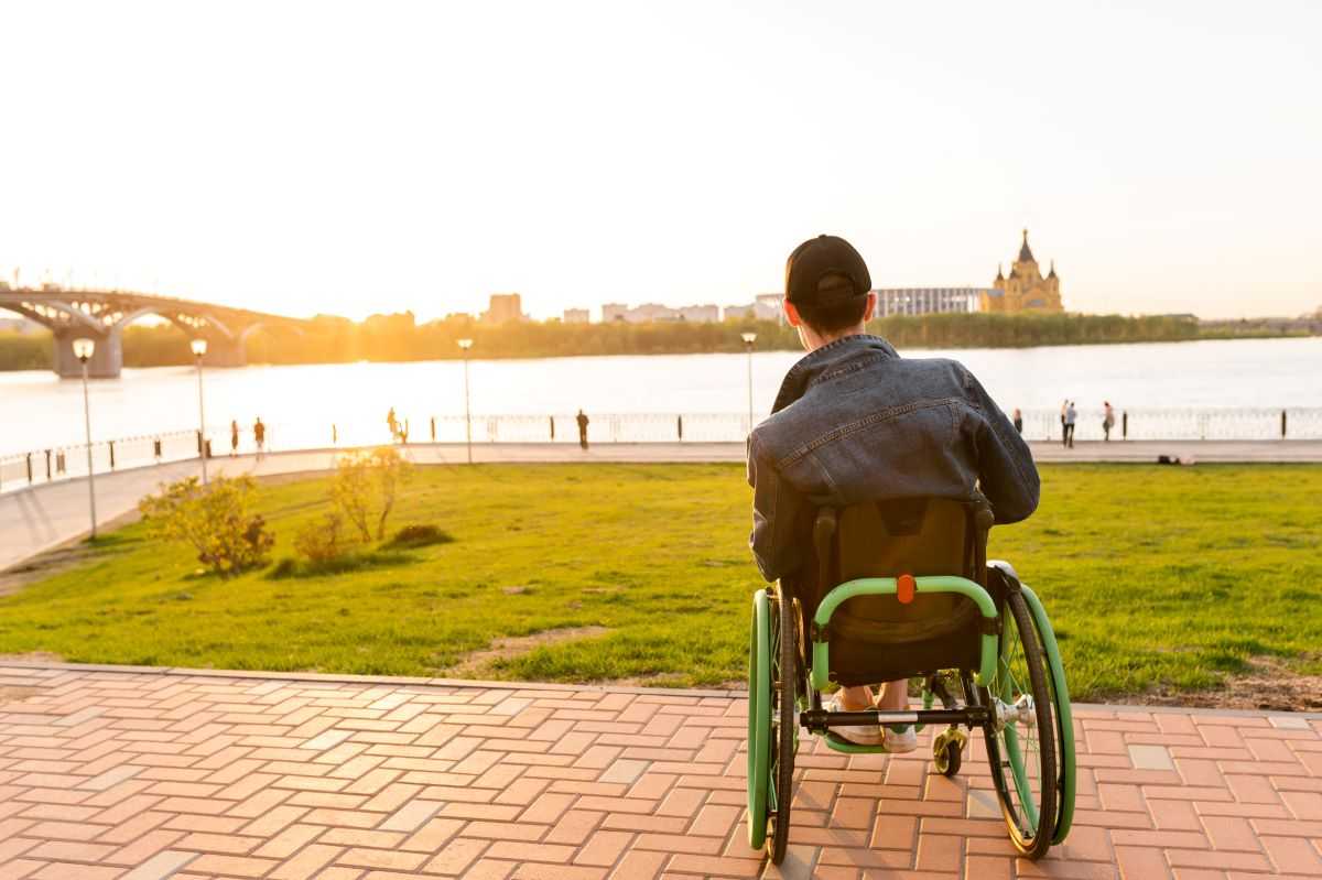Addressing disability stigma and discrimination. Man in wheelchair looking at a river.