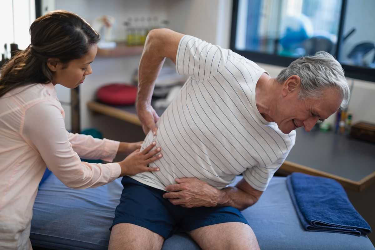 Man consulting physical therapist regarding back pain.
