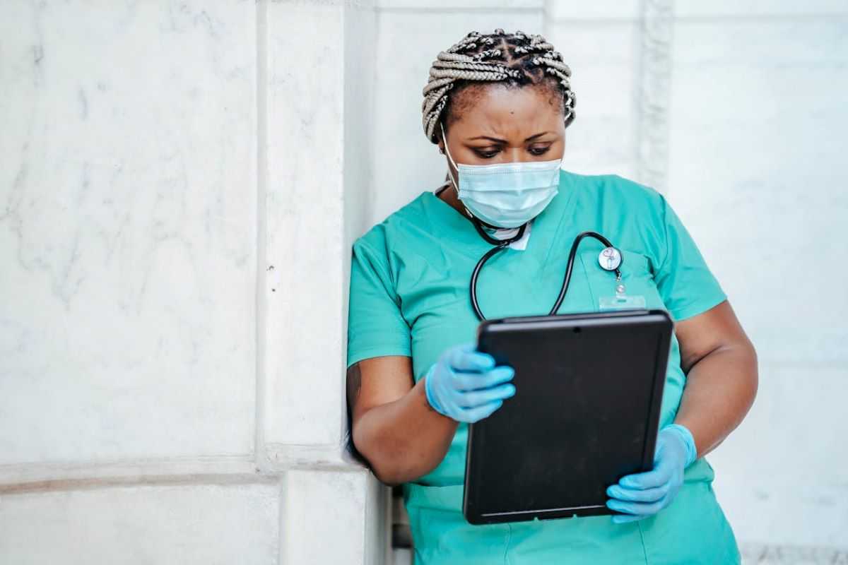 Specialized nurse consults a patient's chart on a tablet.