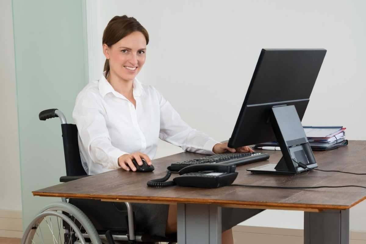 Woman in wheelchair using a computer at work.